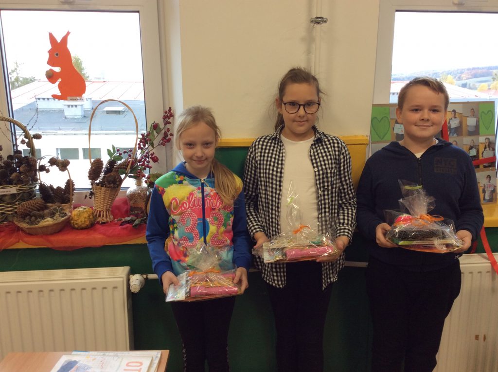 Trzy dziewczynki trzymają przed sobą opakowane celafonem  nagrody za udział w konkursie.