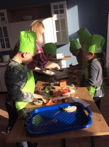 Kilkoro dzieci przygotowuje kanapki i owocowe przekąski.